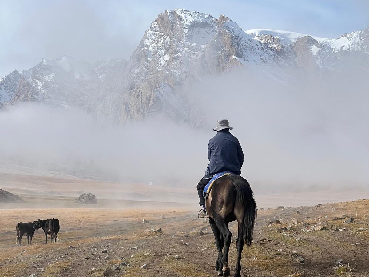 Zamir riding towards a snow-capped peak in the mist